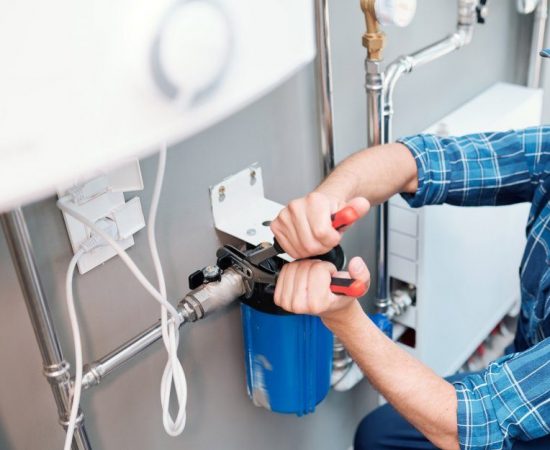 young-man-in-workwear-using-pliers-while-installing-water-filtration-system-e1634566877708